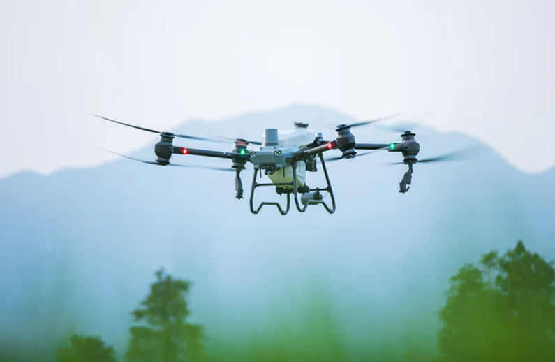 DJI T50 Spraying Drone flying over a snowy landscape with trees in the foreground
