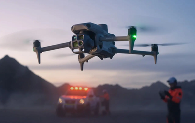 Drone flying over a vehicle with mountains in the background